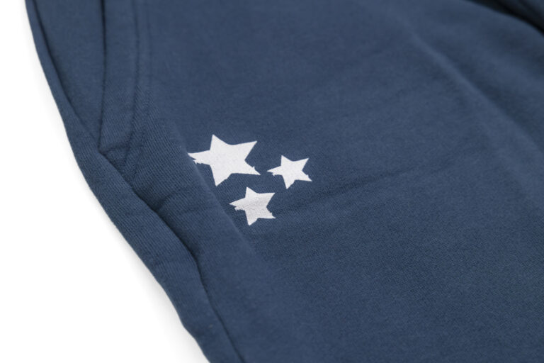 Marineblaue Jogginghose für Herren mit einer Cartoon-Kuhgesichtsgrafik in der Nähe der Tasche und „KUHSTALL“ mit dem stilisierten Logo von Shop Kuhstall auf dem rechten Bein, perfekt für Fans des Kitzloch-Stils.