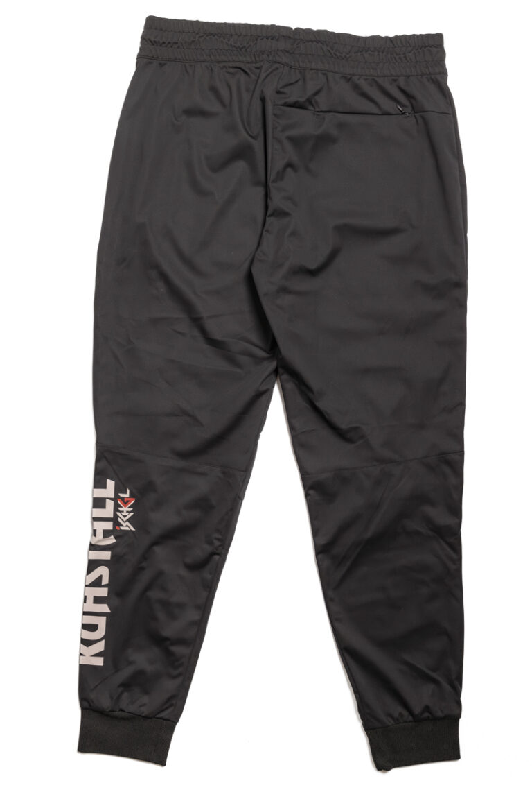 Die schwarze Fleecehose für Herren hat einen elastischen Bund, gerippte Beinabschlüsse, einen weißen Text auf dem linken Bein und ein kleines rotes Logo darüber, das die Essenz des Shops Kuhstall Kitzloch widerspiegelt. Diese Hose mit entspannter Passform wird auf einem schlichten weißen Hintergrund präsentiert.