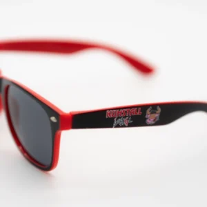 Der Kitzloch-Shop bietet die Sonnenbrille „Kuhstall“ rot | blau mit einem Logo mit dem Text „Kuhstall“ und einem Comic-Stier auf dem Bügel vor einem schlichten weißen Hintergrund an.
