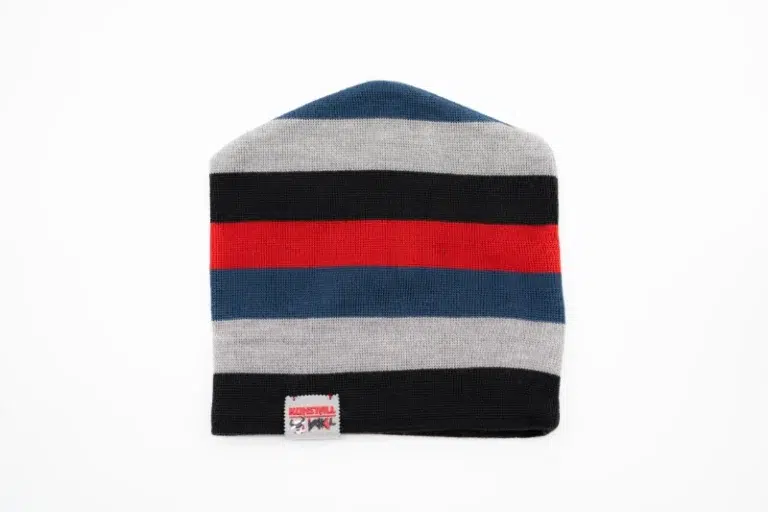 Die Mütze „Stripes“ schwarz rot blau vom Kuhstall Kitzloch zeigt abwechselnd marineblaue, graue, rote und schwarze Querstreifen mit einem kleinen Design-Etikett an der Unterkante auf schlichtem weißem Untergrund.