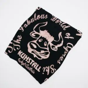 Das Flourad XL schwarz, ein schwarzes T-Shirt vom Kuhstall Kitzloch, ist ordentlich gefaltet auf weißem Hintergrund. Es zeigt rosa Text und eine Grafik eines Stiergesichts mit dem Design „Die fabelhafte Welt von“ und „KUHSTALL #opalustria“.