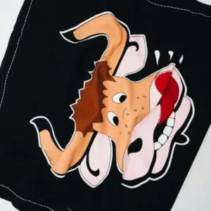 Das Kuhstall Handtuch von Kuhstall Kitzloch besteht aus schwarzem Stoff mit der Karikatur einer hellbraunen, braunen und rosa Tierfigur mit großen Hörnern, einem offenen, lächelnden Mund, weißen Augen und einer roten Zunge vor einem kontrastierenden Hintergrund.