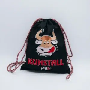 Der Kuhstall Rucksack, erhältlich im Kuhstall Kitzloch Shop, ist ein schwarzer Kordelzugbeutel, der mit einer verspielten Cartoon-Kuh verziert ist, die ihre Zunge herausstreckt. Unter der Kuh steht prominent in Rot „KUHSTALL“ mit einer stilisierten weißen Signatur darunter.