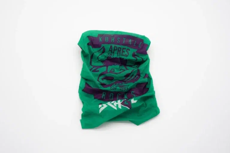 Ein zerknittertes grünes Produkt vom Kuhstall Kitzloch mit dem Text „Kuhstall“, einem auffälligen Tier mit Sonnenbrille, liegt auf einem weißen Hintergrund.